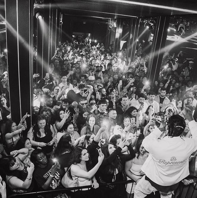 A large crowd at a concert, with bright lights and beams illuminating the scene.